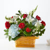 Basket arrangement of red roses, white lilies, and blue hydrangeas