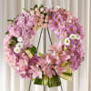 Pink floral wreath on a black easel with lilies and daisies