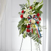 Standing floral spray with white lilies, red carnations, and a patriotic ribbon