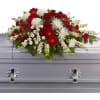 Red and white floral spray on a gray casket