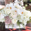 White floral arrangement in a rectangular wooden box with orchids and roses
