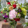 Mixed bouquet of roses, hydrangeas, and assorted blooms in a glass vase