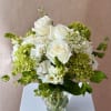 White roses and green hydrangeas in a clear glass vase