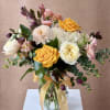 Bouquet of yellow, white, pink, and purple flowers in a glass vase with a ribbon