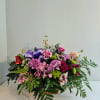 Mixed bouquet of pink and purple flowers in a basket with a purple ribbon