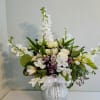 White floral arrangement in a speckled vase with a white ribbon