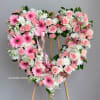 Heart-shaped floral wreath with pink roses and gerbera daisies on an easel