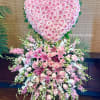 Heart-shaped pink rose arrangement above a cascading pink lily bouquet