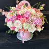 Pink and white mixed flower arrangement in a round pink box
