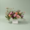 Mixed pink, peach, and purple flowers in a white vase