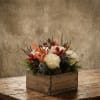 White roses and orange calla lilies in a wooden box