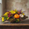 Fall floral arrangement with pumpkins on a bark base
