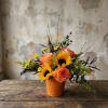 Orange roses and sunflowers arranged in a small terracotta pot