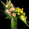 Peach, pink and sunny yellow roses spill from a tall clear glass