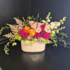 A lush, garden-style bouquet arranged low in a wide ceramic container, this