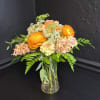 Bright orange ranunculus take center stage in this cheerful flower arrangement, paired