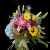 Mixed bouquet with pink lily, sunflowers, and blue hydrangea in a glass vase