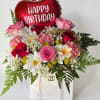 Pink and red flower arrangement with a heart-shaped Happy Birthday balloon in a white bag