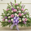 Large pink and white floral arrangement with a purple ribbon bow