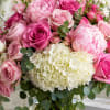 A lush cascade of pink roses and pale peonies greets the eye-the