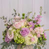 A lush, garden-style bouquet in soft blush pinks, lavender purples, crisp white
