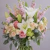 Soft pink roses and large white lilies mingle with pale peach spray