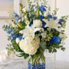 Crisp white lilies and roses meet vivid blue delphinium and accent blooms