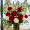 A striking upright display of vivid red roses and creamy white blooms
