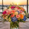 A lush, rounded bouquet of pastel and jewel-toned blooms that reads like