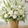 A soft, serene centerpiece of white roses, lilies, carnations and clustered blooms