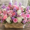 A lush, garden-style basket overflowing with soft pink roses and lilies sets