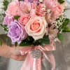 A soft, romantic handheld nosegay in pinks and purples that reads like