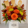 Autumn floral arrangement in a white utensil holder with wooden kitchen tools