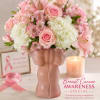 Pink and white floral arrangement in a pink vase with a candle and awareness ribbon