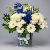 Soft cream roses and crisp white daisies are lifted by vivid blue