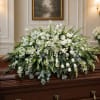 A cloud of pure white blooms draped across the casket creates a