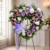 A tender heart-shaped standing spray in soft purples and pastels that gently