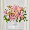 Pink lilies and peach roses in a white pedestal vase