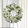 White floral wreath on a black stand with daisies and roses