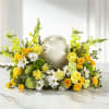 Yellow roses and white daisies arranged around a silver urn