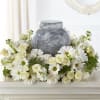 White daisies and roses arranged around a gray urn-shaped vase