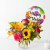 Mixed flower bouquet in a glass vase with a Happy Birthday balloon