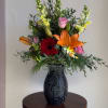 Mixed bouquet in a black vase with lilies, roses, and a red gerbera daisy