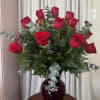Red roses arranged in a dark glass vase with eucalyptus