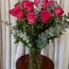 Hot pink roses in a clear glass vase with eucalyptus