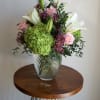 A fresh and elegant arrangement featuring lush green hydrangeas, classic roses, and