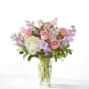 Pink roses and lavender flowers arranged in a clear glass vase