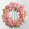 Pink floral wreath on a black stand