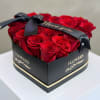 Red roses arranged in a black heart-shaped box with a ribbon