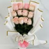 Hand-tied bouquet of light pink roses wrapped in sculpted white paper with gold trim